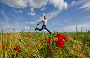 Lebensfreude: Mann springt ber Sommerwiese